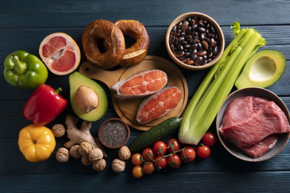 Sélection d'aliments anti-inflammatoires : saumon, avocat, légumes colorés, noix et gingembre sur fond bois